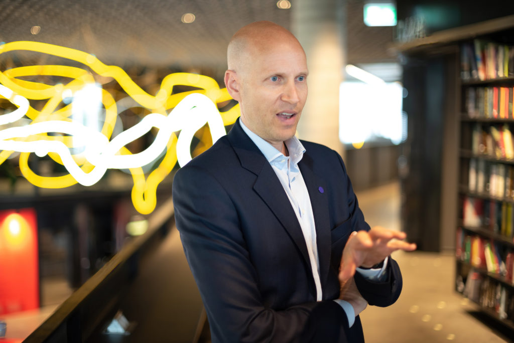 Håkon Volldal talking to camera inside a library