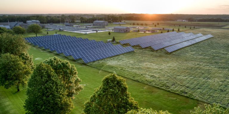 Solar cell panels on a large green field at sunrise