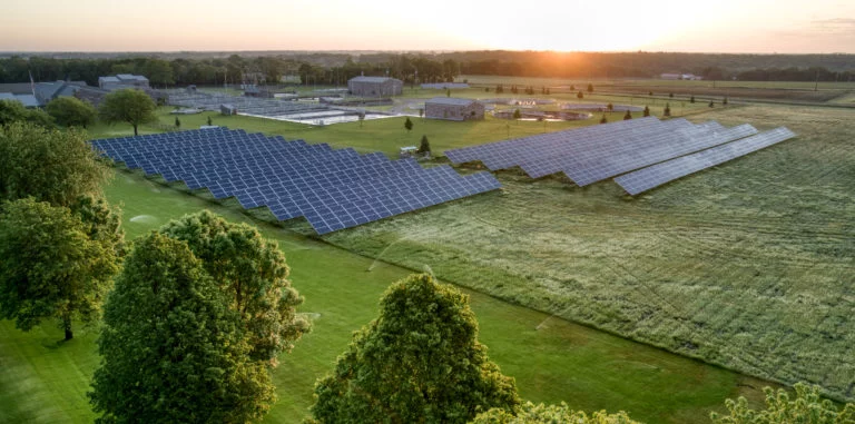 Solar cell panels on a large green field at sunrise